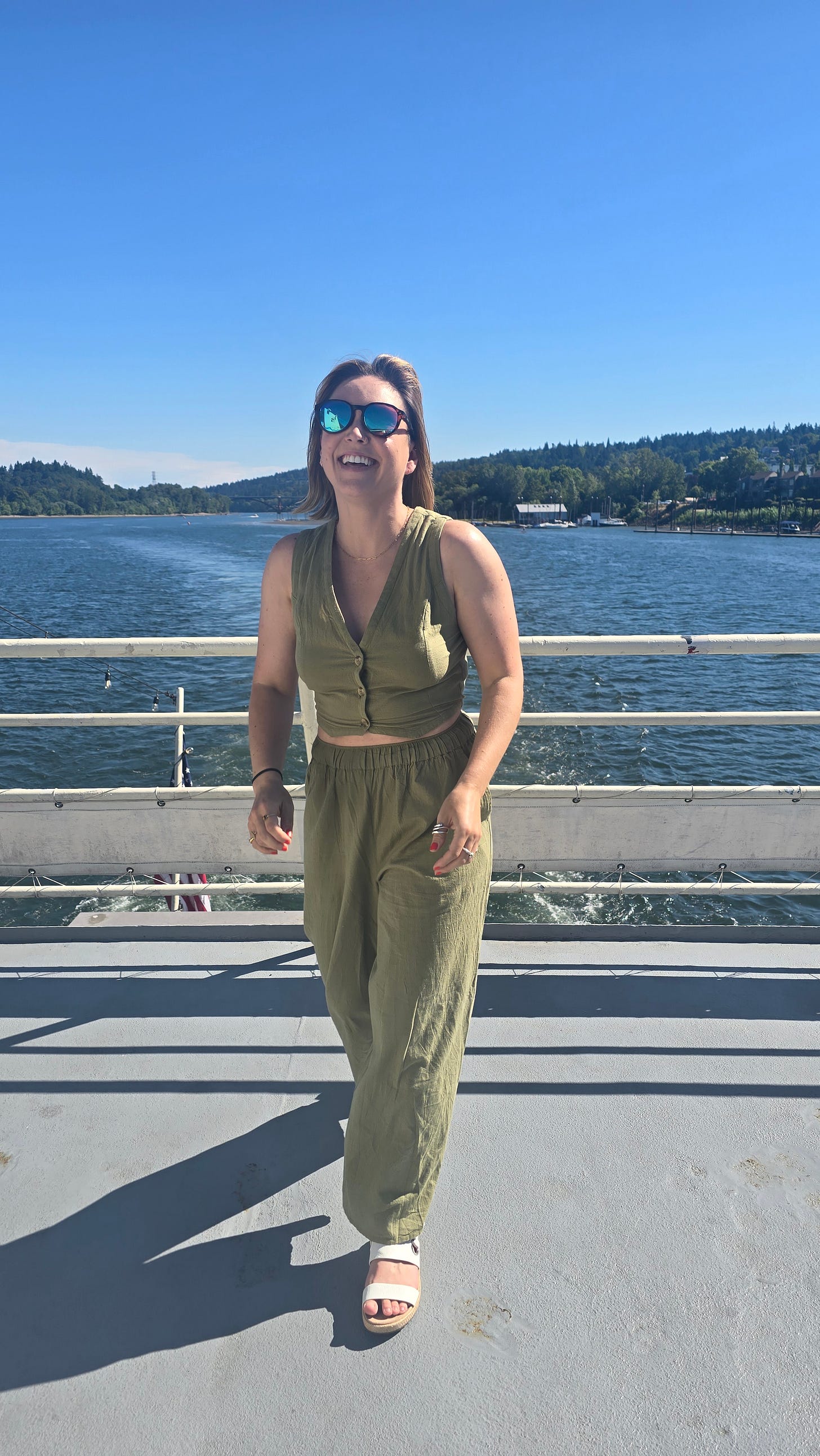 Cassidy walking on a boat wearing a green linen outfit, smiling