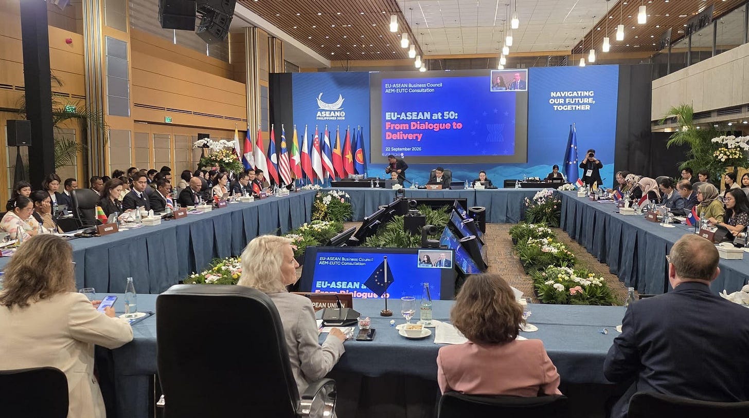 Government and enterprise executives from Southeast Asia and Europe gathered around a large U-shaped conference table during the 12th ASEAN-EU Business Summit in Manila, with a main backdrop screen displaying "EU-ASEAN at 50: From Dialogue to Delivery" alongside member state flags