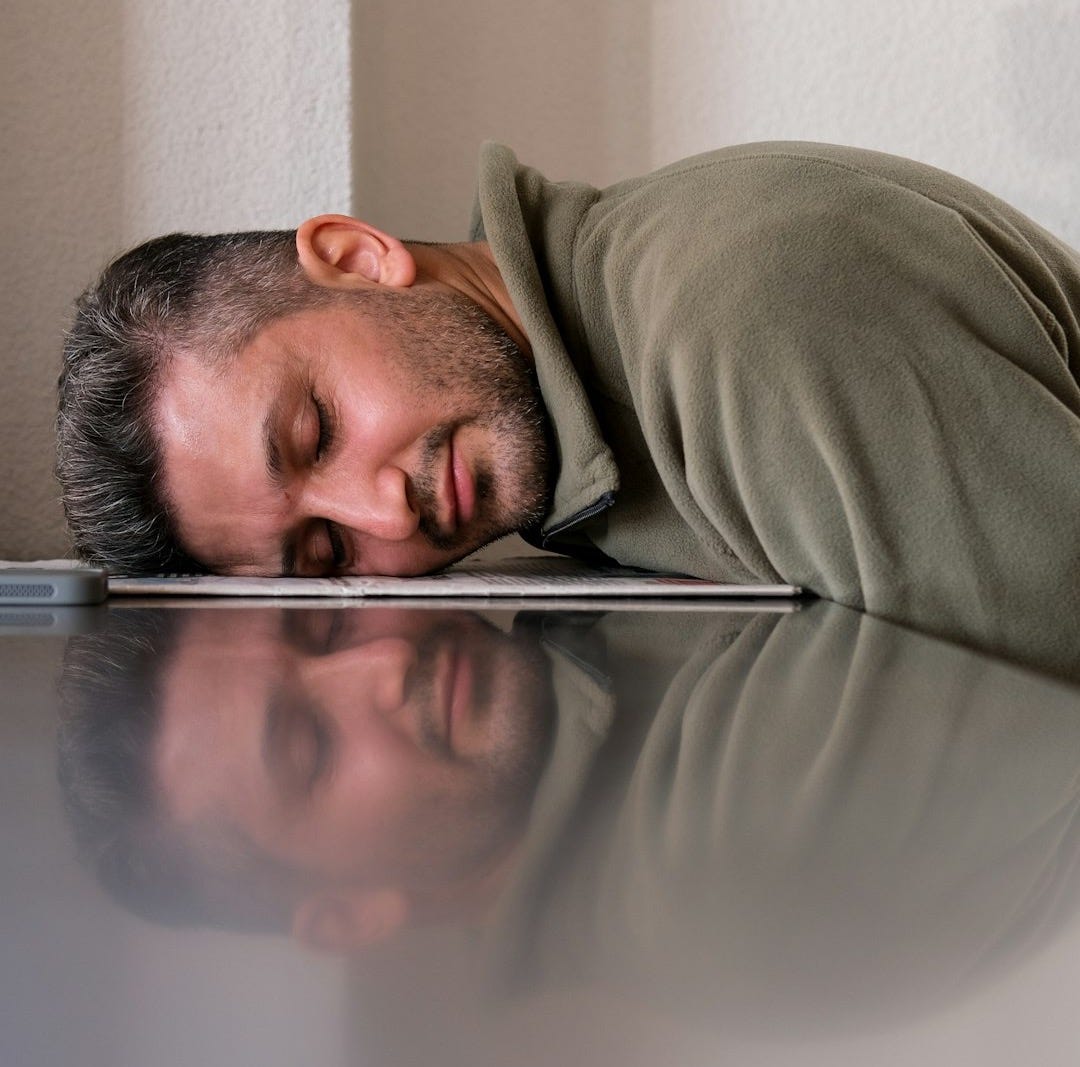 A man is sleeping on the floor with his head on a laptop