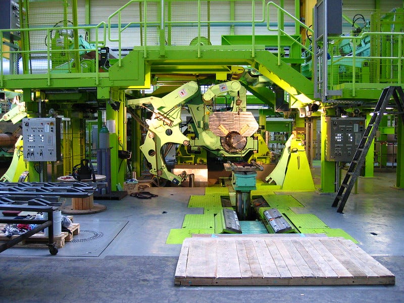 a color photo of an industrial interior space that holds a lot of bright green machinery