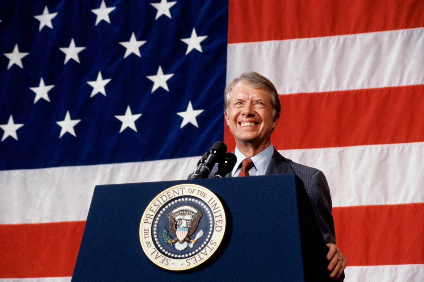 President Jimmy Carter smiling as he addresses a town meeting.