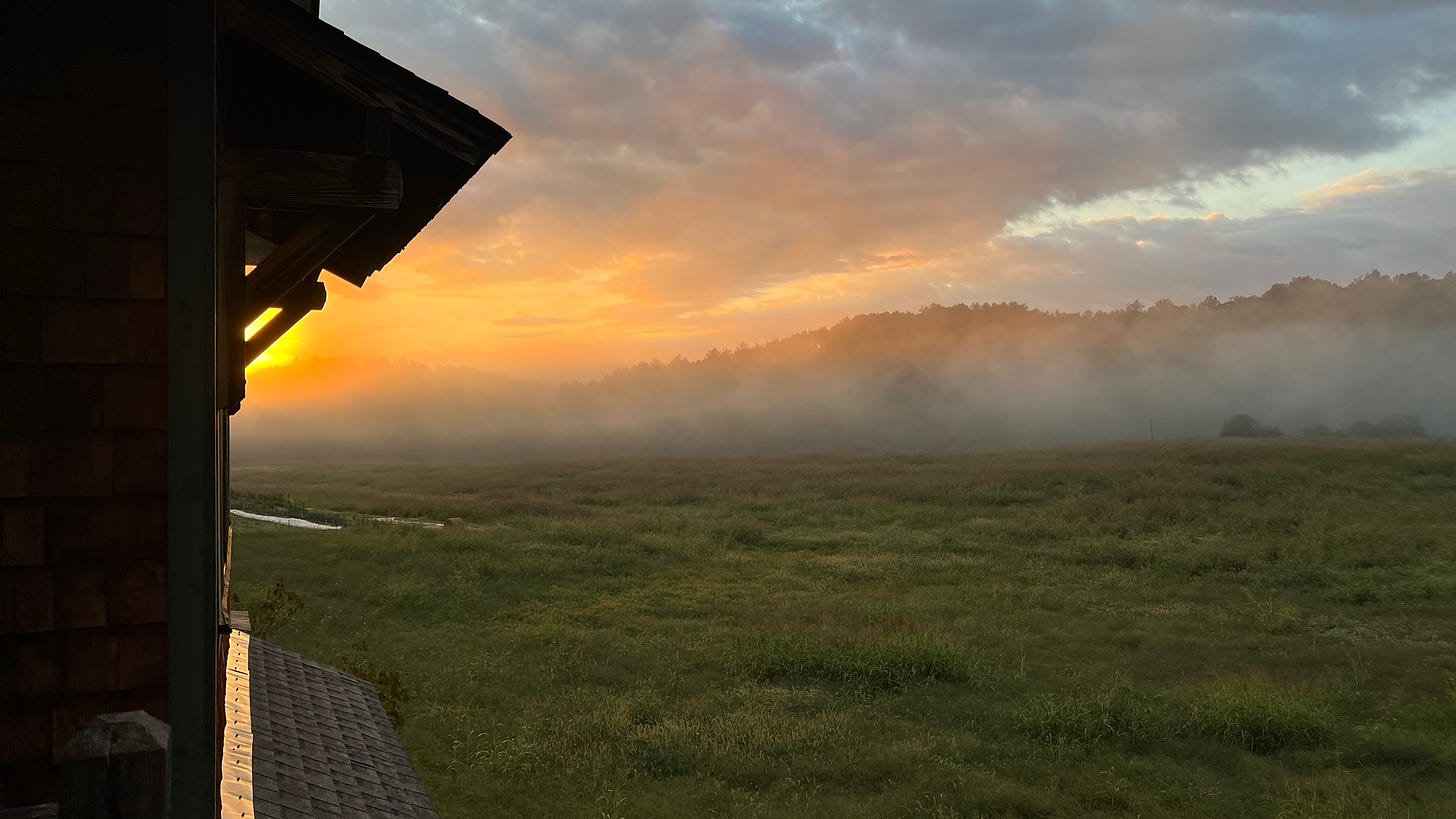 a sunrise with clouds, mist and a building