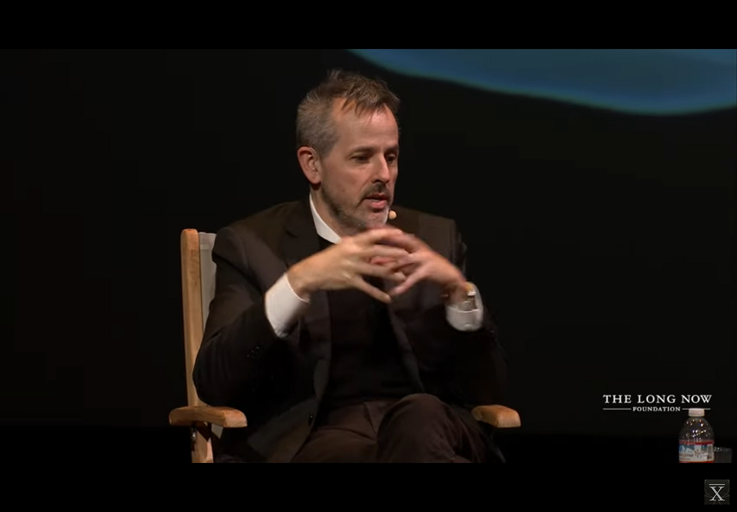 Benjamin Bratton sitting with hands together while answering a question during the Q&A portion of his Long Now talk on Planetary Computation