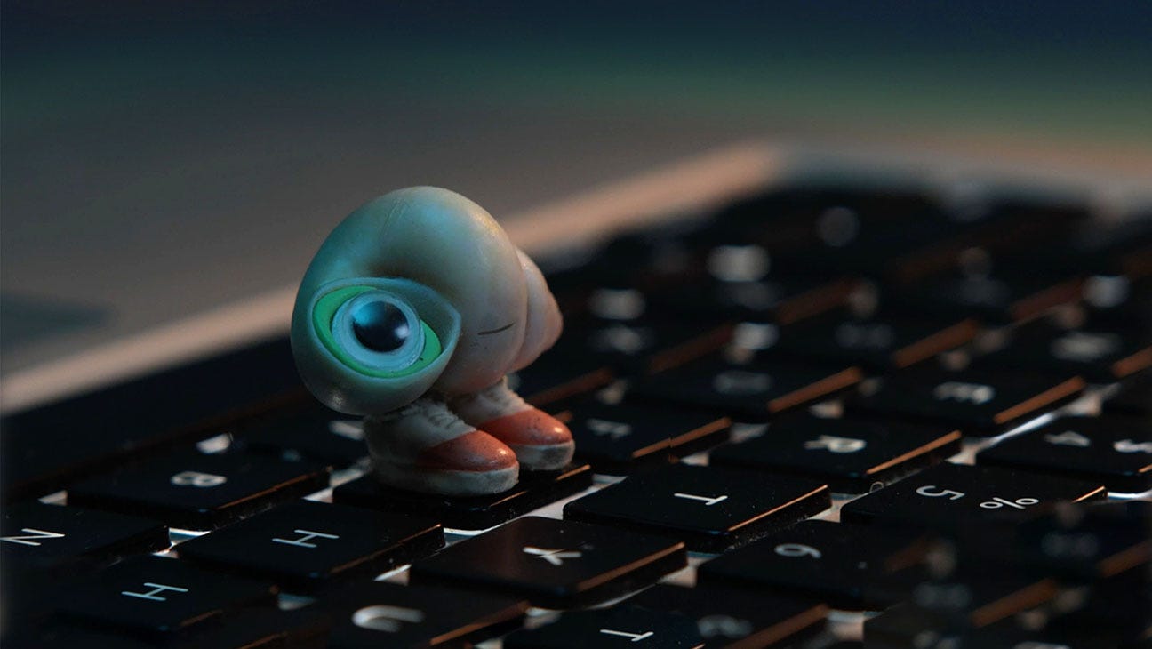 Marcell the Shell with Shoes On stares up at a computer screen, standing on one key of the keyboard. Marcell the Shell with Shoes On stares up at a computer screen, standing on one key of the keyboard.