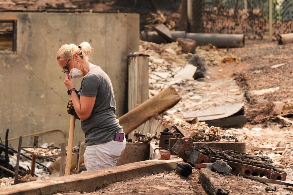 Jana Jensen sifts through the remains of her parents' home after a wildfire hit the northern part of Spokane, Wash., Monday, Aug. 3, 2026. Jana Jensen sifts through the remains of her parents' home after a wildfire hit the northern part of Spokane, Wash., Monday, Aug. 3, 2026.