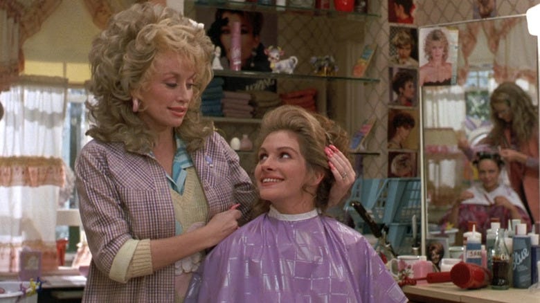 Still from Steel Magnolias shows the Dolly Parton character styling the hair of Julia Roberts' Shelby.