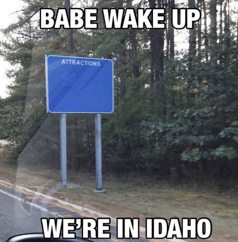 a blue road sign sitting on the side of a road next to a lush green forest