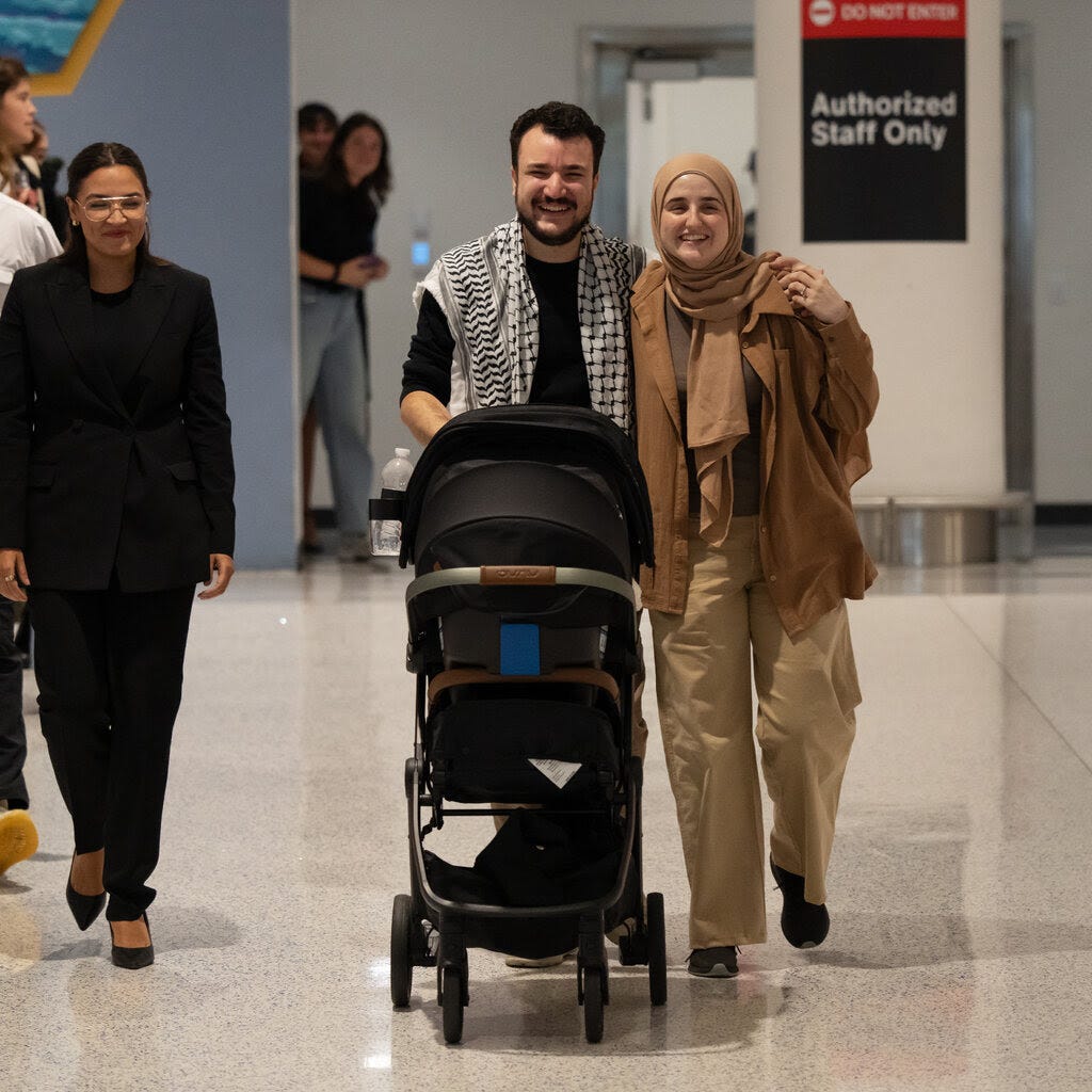 Mahmoud Khalil pushing a stroller through an airport while embracing his wife. Alexandria Ocasio-Cortez looks on.