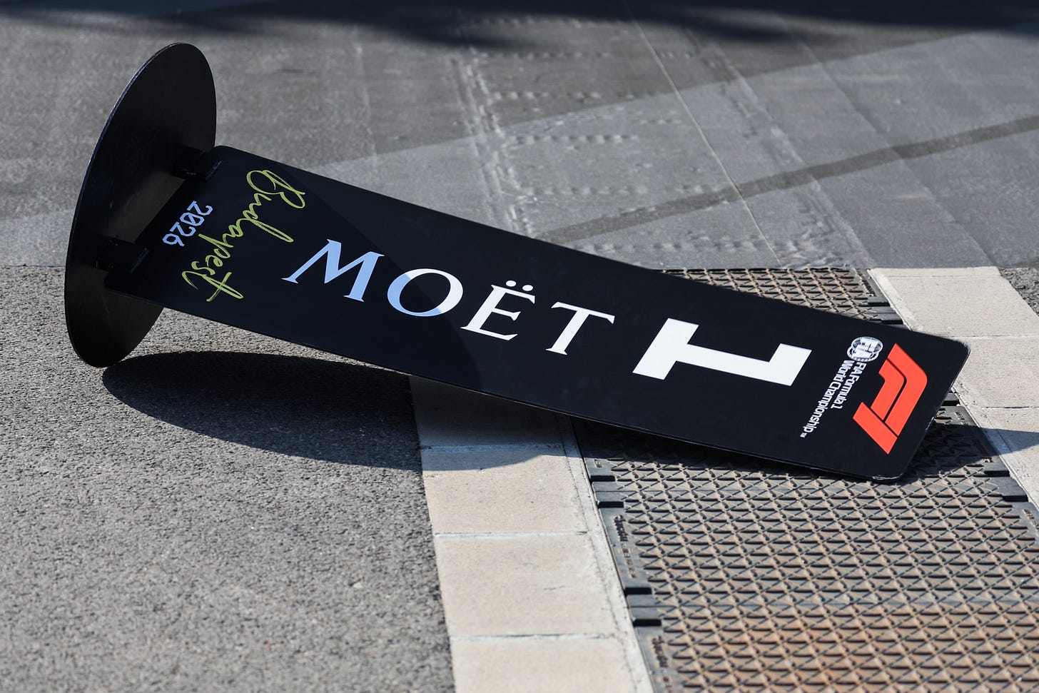 A first-place market board on its side after having been blown over by wind in the pit lane