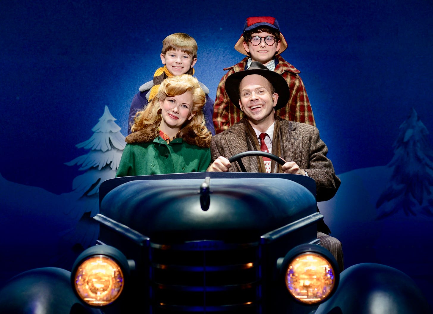 A family of four drives through a snowy landscape