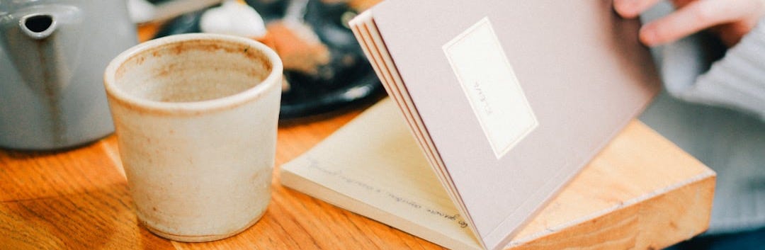 person opening book near coffee cip person opening book near coffee cip