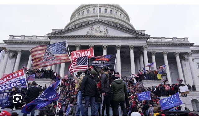 A group of people holding flags and standing in front of a building

Description automatically generated