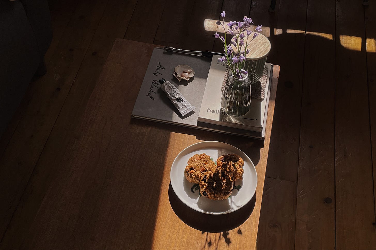 Coffee table in soft light with a plate of three blueberry oat cookies; the rest of the space is in gentle shadow.