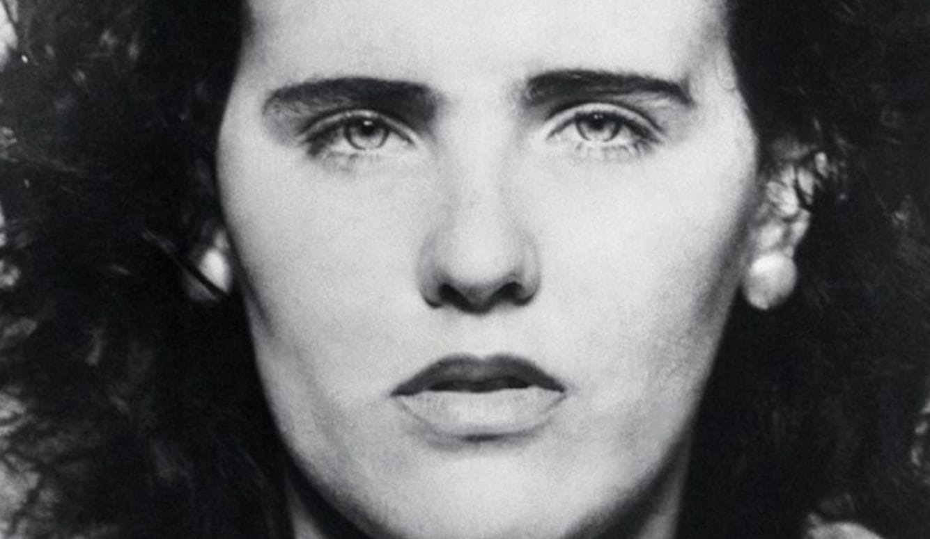 Black and white photo of a woman’s face in close-up. She is young, with pale skin and dark hair. 