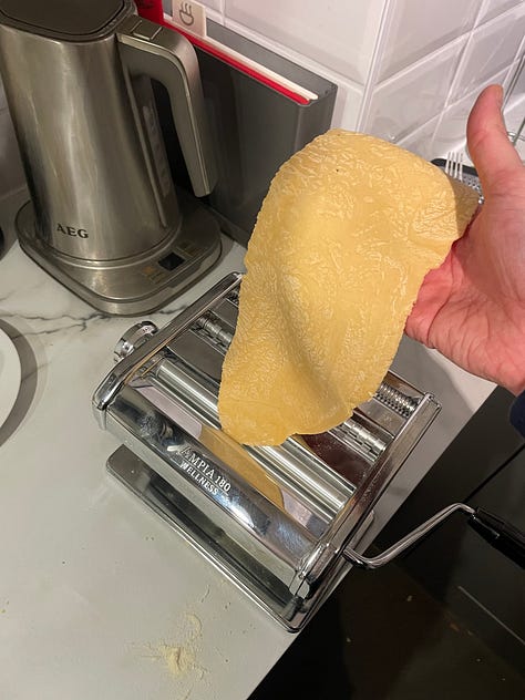 Steps for making tortellini from fresh using a pasta machine illustrated. The pasta is rolled before cut into squares, with a small amount of filling added and then folded into a triangle before the bottom two corners are tied around