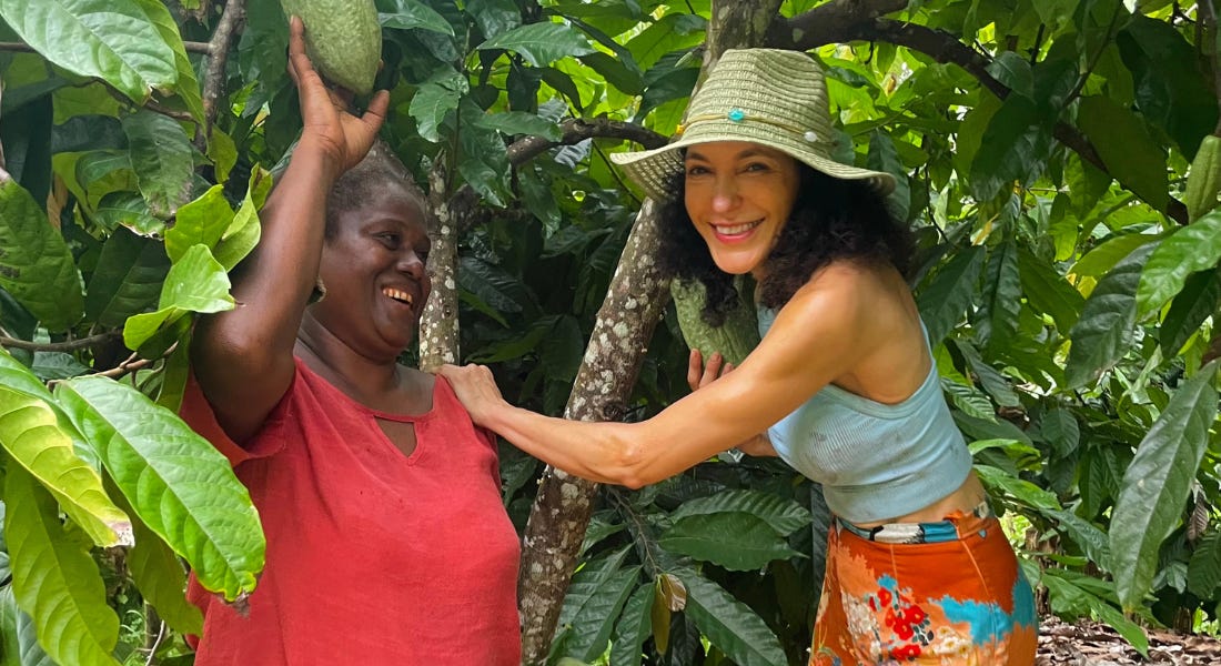 Two women standing in front of a cocoa tree, smiling into the camera Two women standing in front of a cocoa tree, smiling into the camera