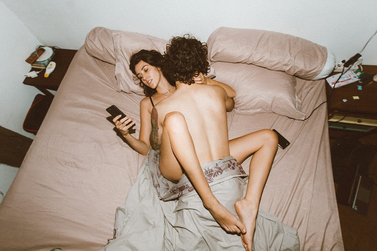 Man/woman having missionary sex, woman turned away looking at her cell phone