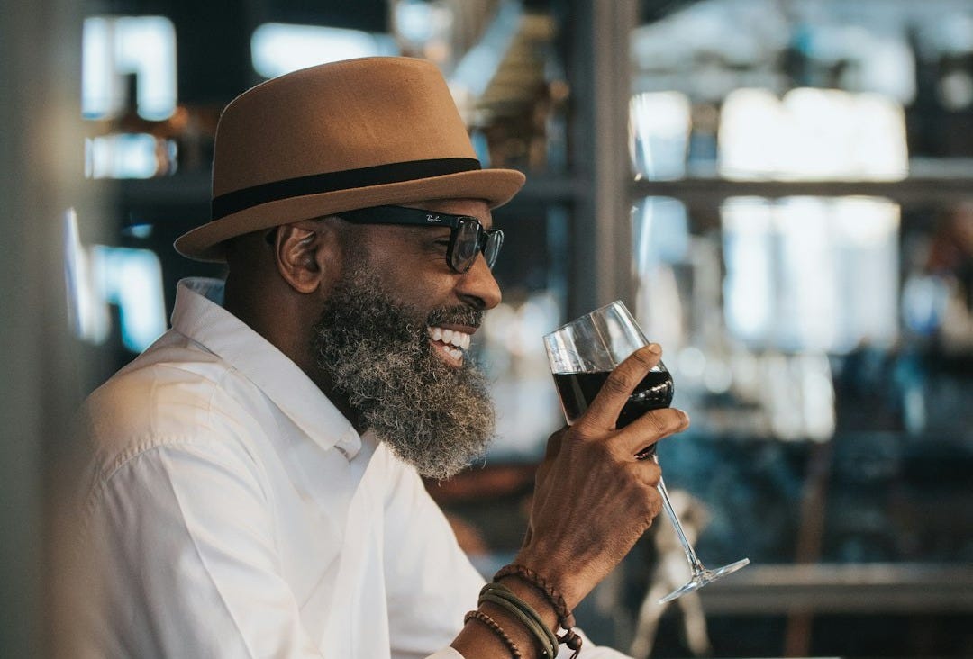 man in white dress shirt and brown hat holding clear drinking glass man in white dress shirt and brown hat holding clear drinking glass