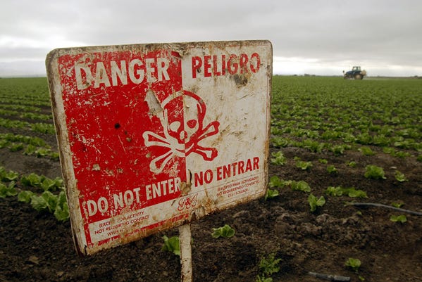 A "Do Not Enter" sign marks a field of cabbage during the spraying of pesticides.