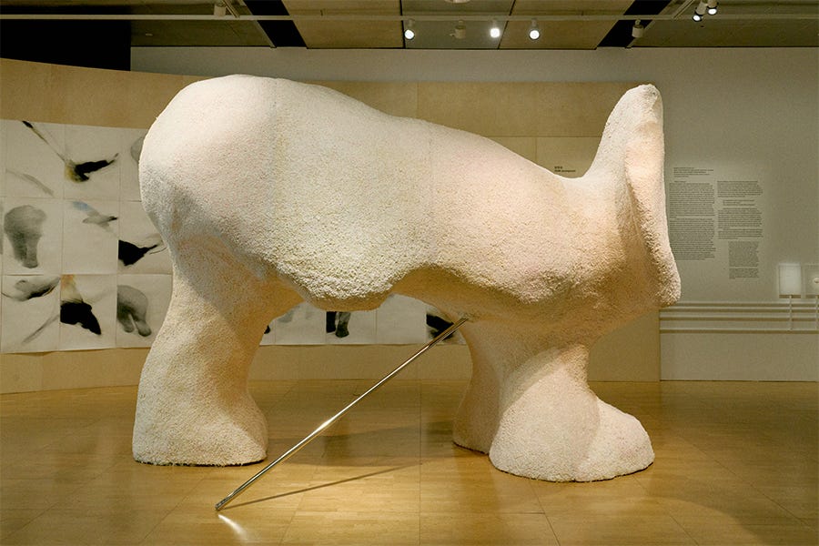 A large sculpture made of styrofoam of a polar bear without a head or 4th leg.