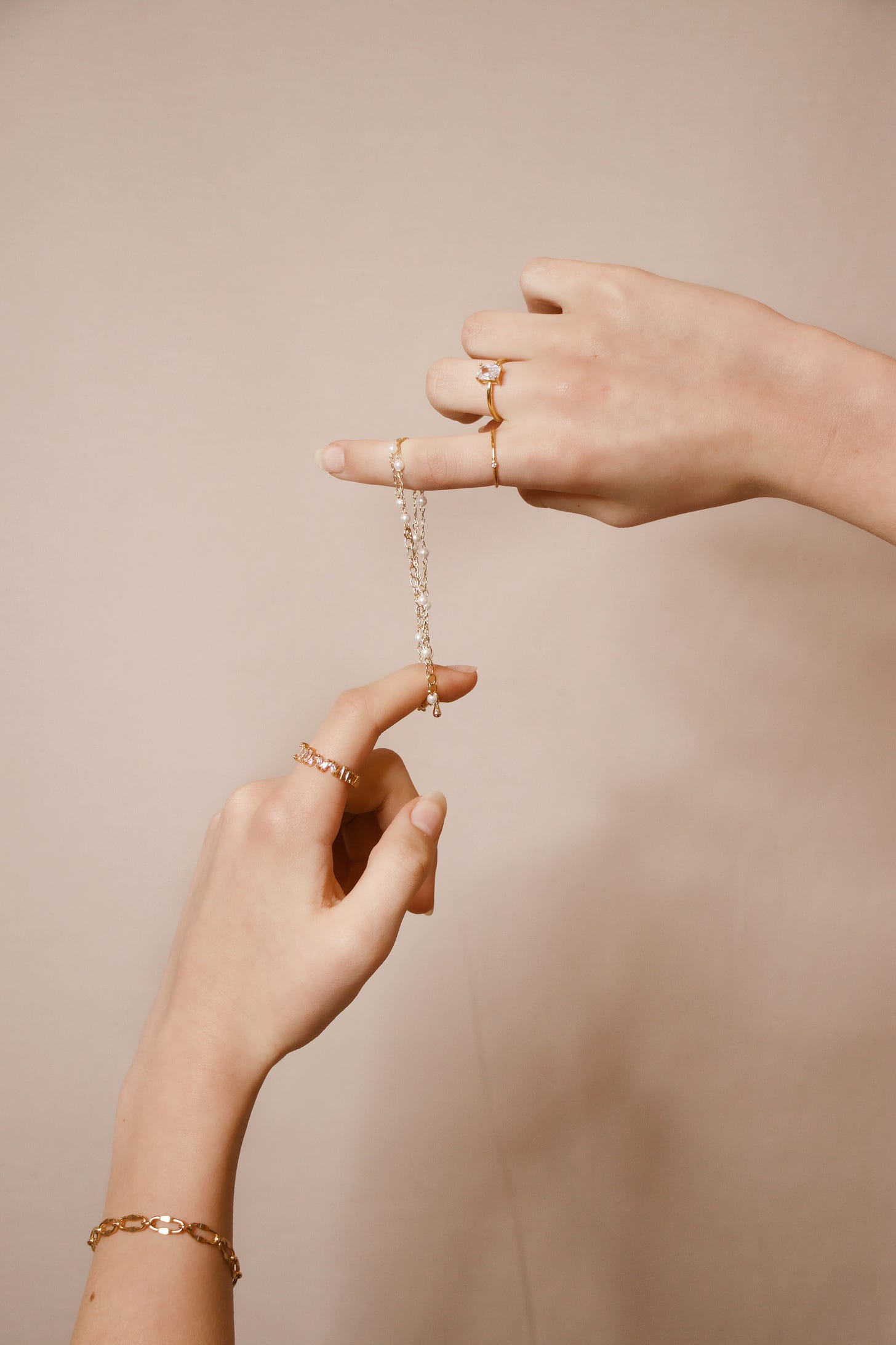 image of two hands, one above each other, holding a thin gold bracelet