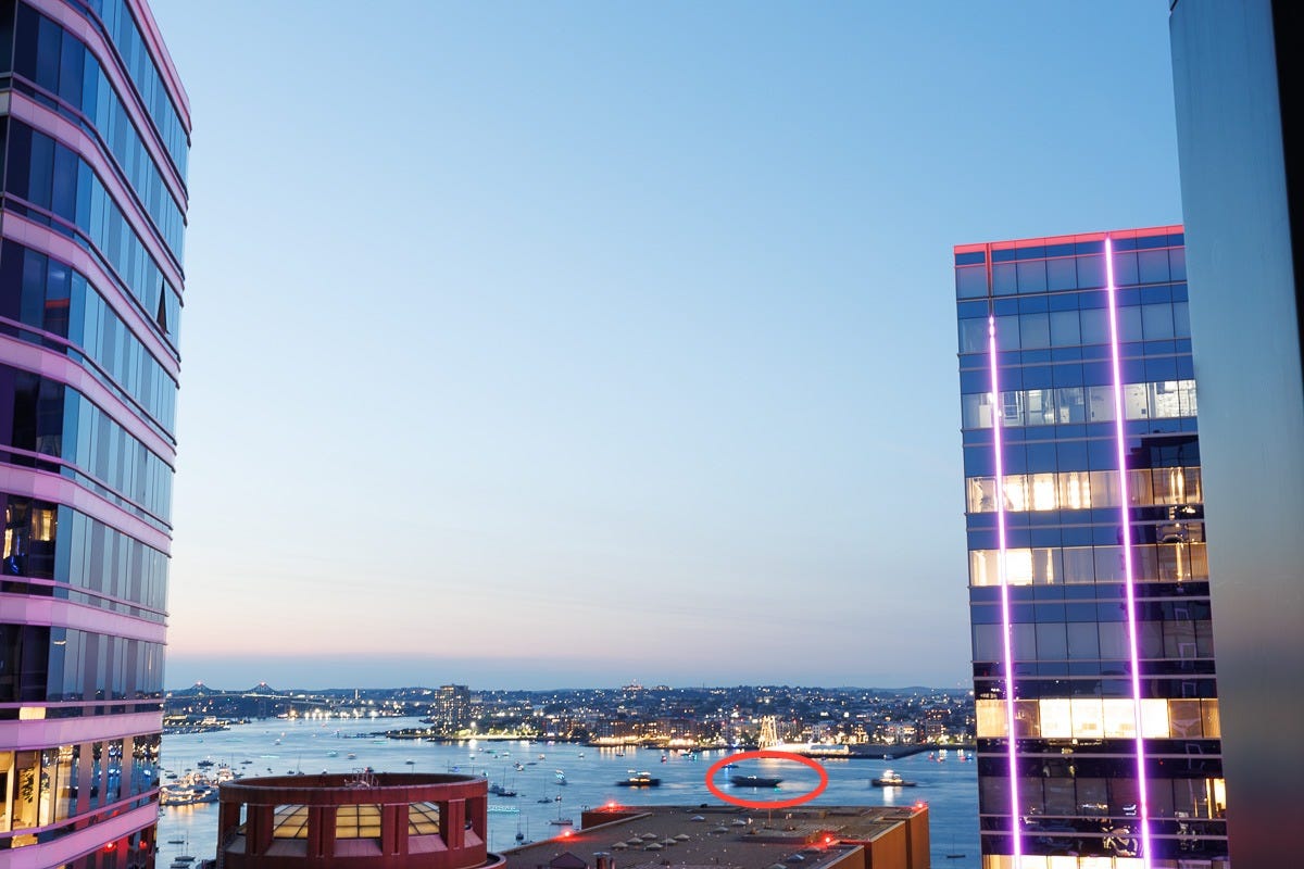 Evening harbor view between two modern buildings with boats preparing for fireworks in Boston Seaport Evening harbor view between two modern buildings with boats preparing for fireworks in Boston Seaport