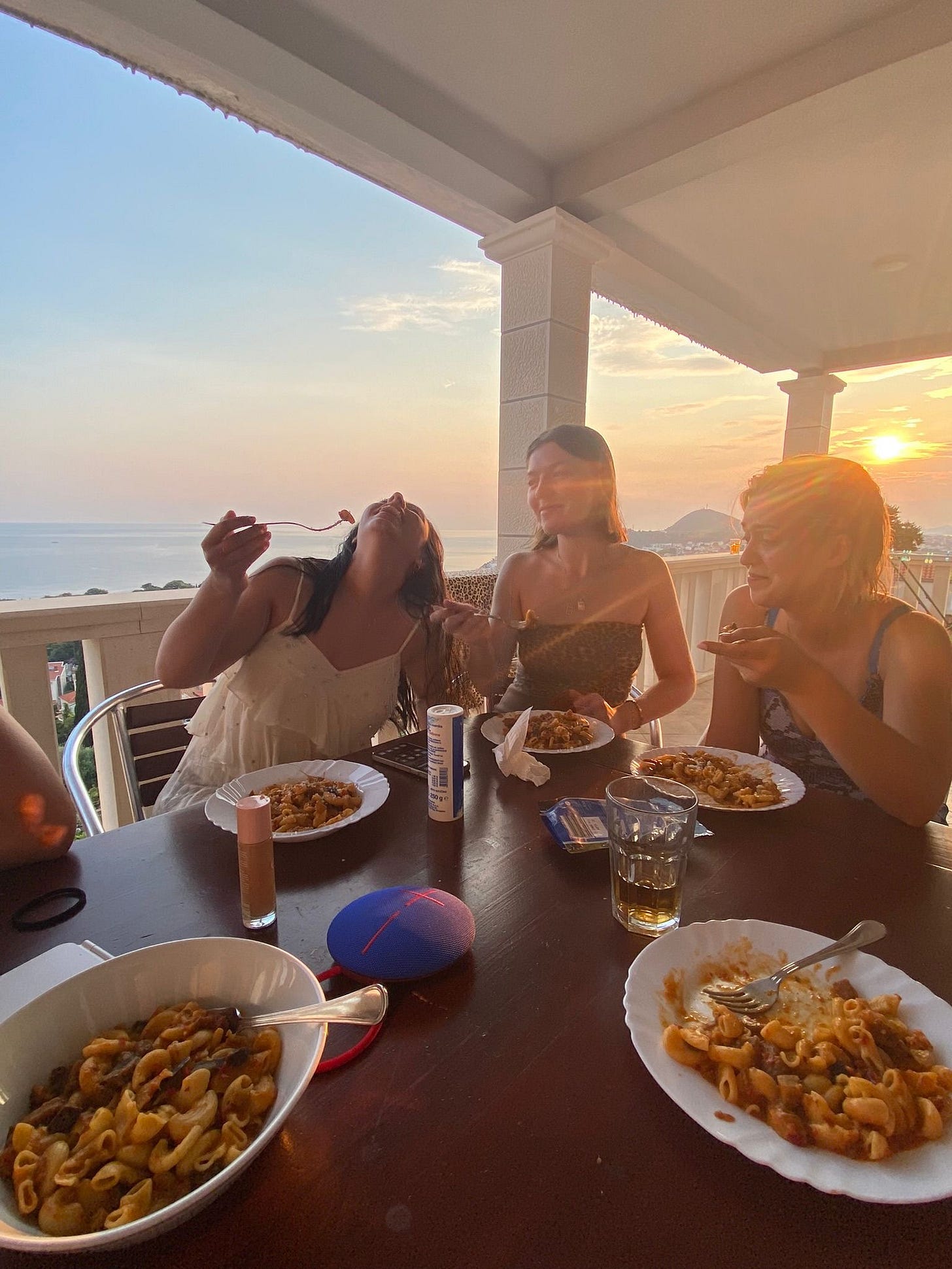 Me with two friends eating pasta on the balcony under the sunset