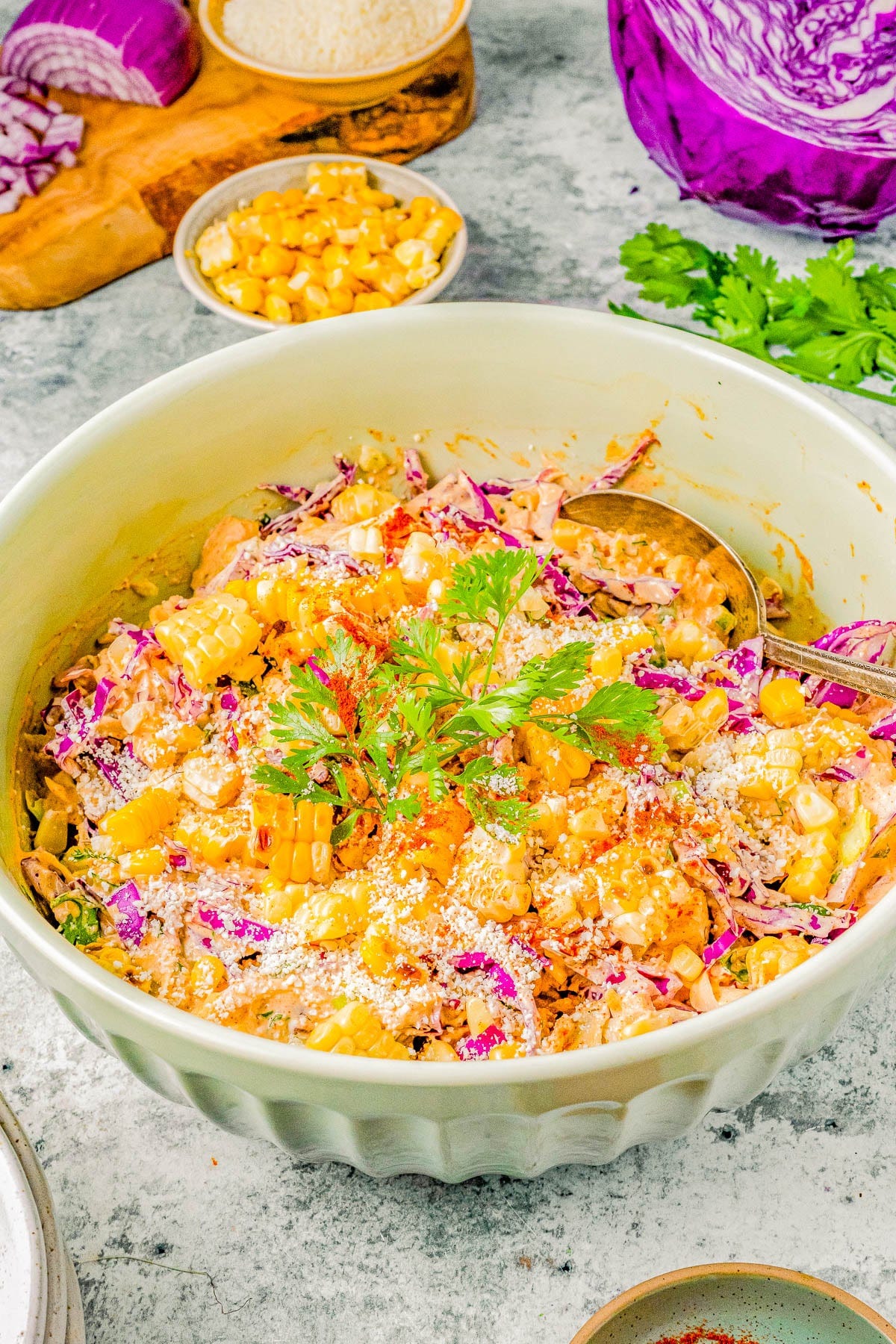 A vibrant bowl of corn salad mixed with shredded purple cabbage, topped with fresh herbs and sesame seeds.
