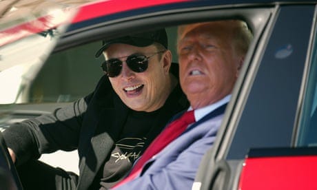 a man in a suit and a man in black clothes sit in a red car a man in a suit and a man in black clothes sit in a red car