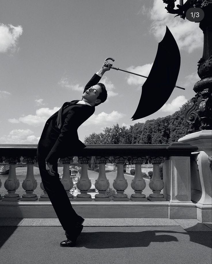 This may contain: a man in a suit holding an umbrella This may contain: a man in a suit holding an umbrella