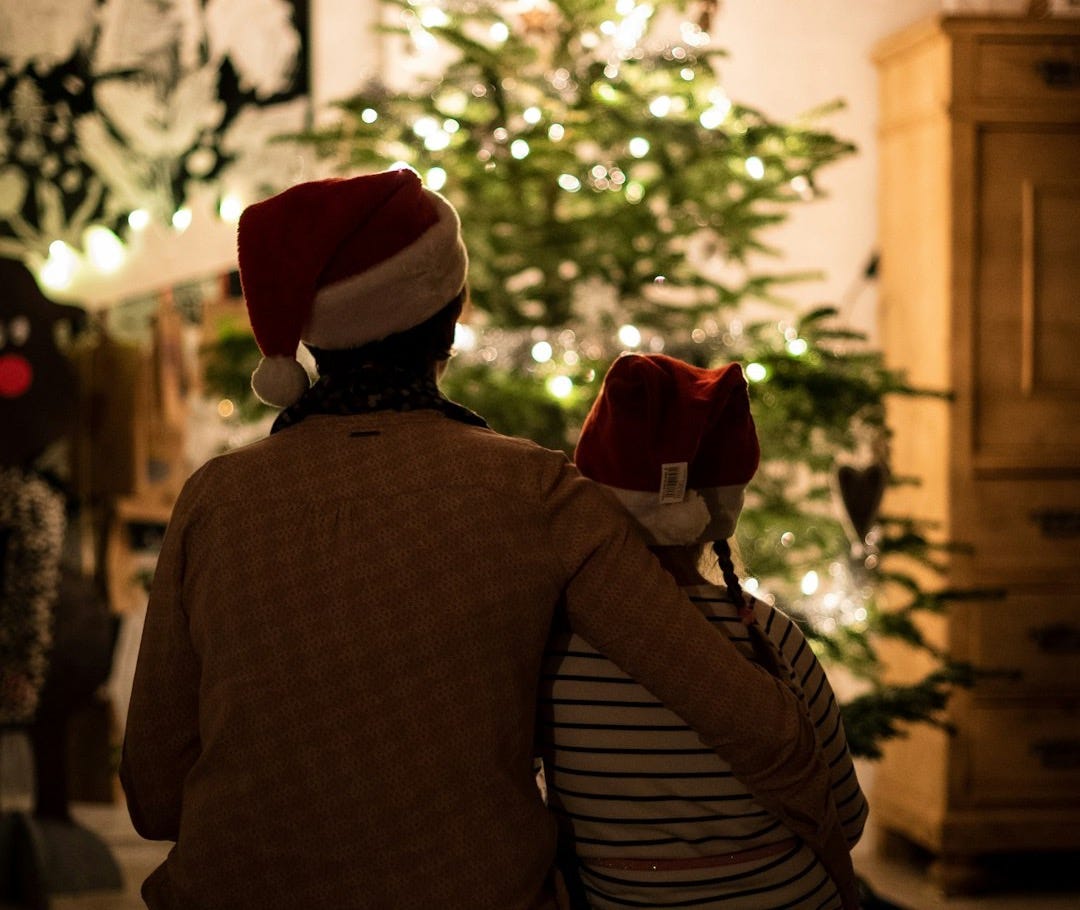 selective focus photography of girl an woman hugging each other in front of christmas tree