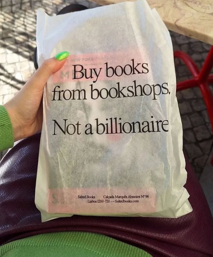 This may contain: a person holding up a book bag with the words buy books from bookshops, not a billionaire