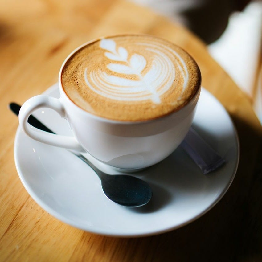 white ceramic cup with latte cafe art on desk white ceramic cup with latte cafe art on desk
