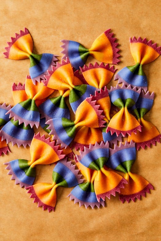 rainbow colored bow tie pasta on a sand colored background rainbow colored bow tie pasta on a sand colored background