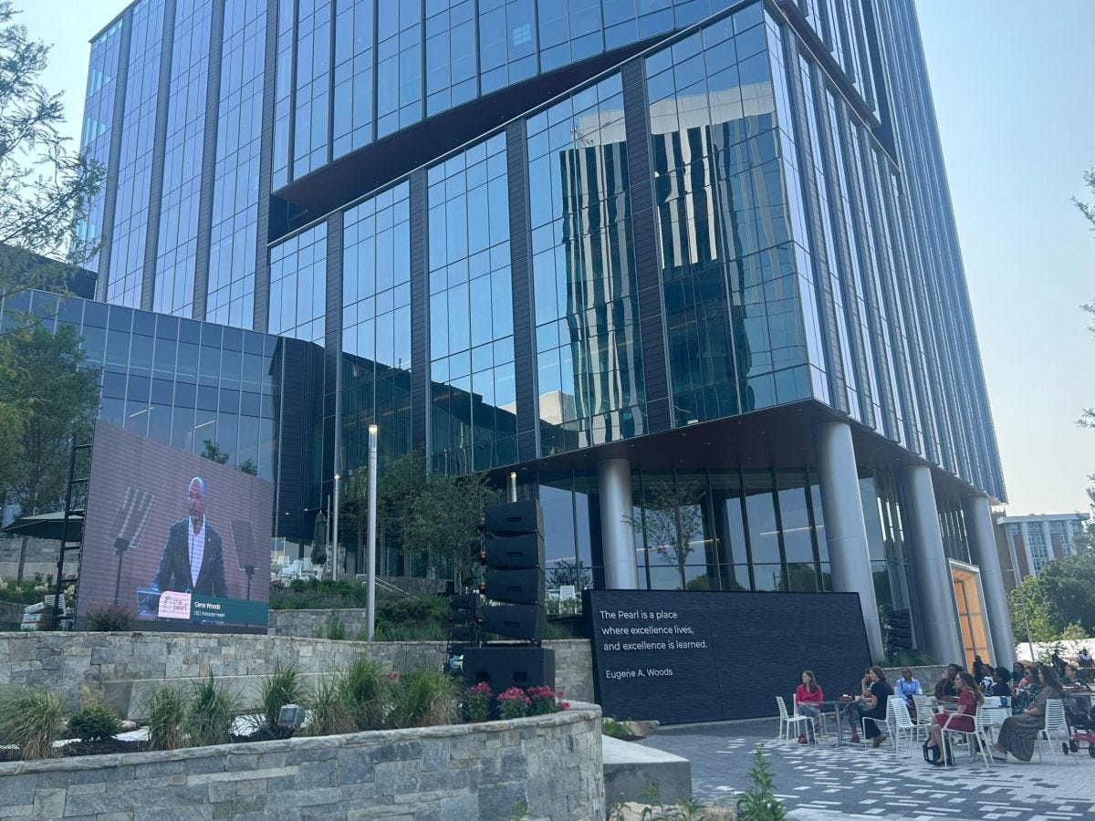 A man speaking on a screen in front of a large glass building and people sitting at tables at the opening of Atrium Health's medical district, The Pearl. The hospital promised to build affordable housing when it asked for $75 million in public money for its new medical district, called The Pearl. But the housing hasn't materialized. A man speaking on a screen in front of a large glass building and people sitting at tables at the opening of Atrium Health's medical district, The Pearl. The hospital promised to build affordable housing when it asked for $75 million in public money for its new medical district, called The Pearl. But the housing hasn't materialized.