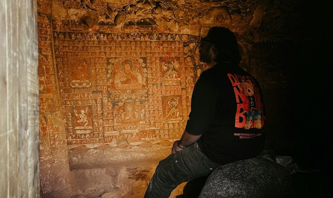 A person sitting on a rock in a cave A person sitting on a rock in a cave
