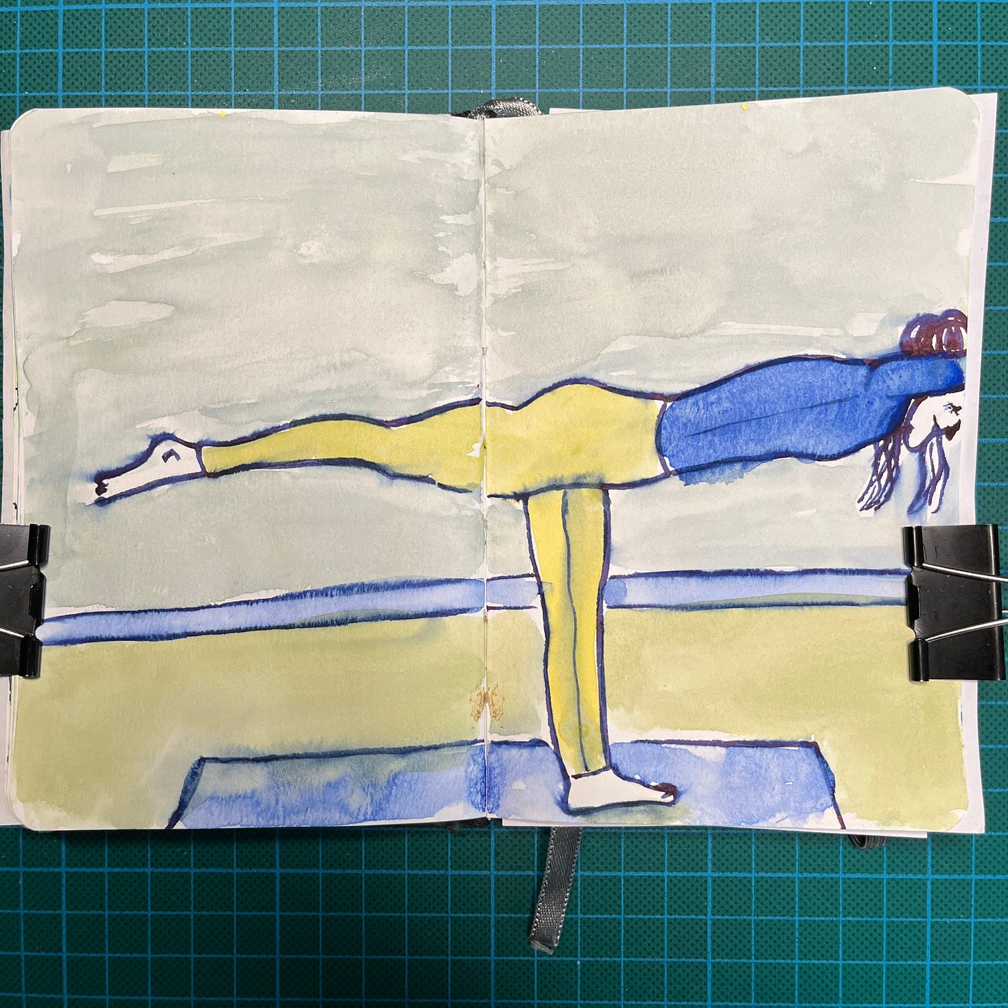 Posé sur mon tapis de découpe, mon sketchbook ouvert sur la double-page où j'ai fait le dessin du Jour 25 : une personne en position de yoga. Posé sur mon tapis de découpe, mon sketchbook ouvert sur la double-page où j'ai fait le dessin du Jour 25 : une personne en position de yoga.