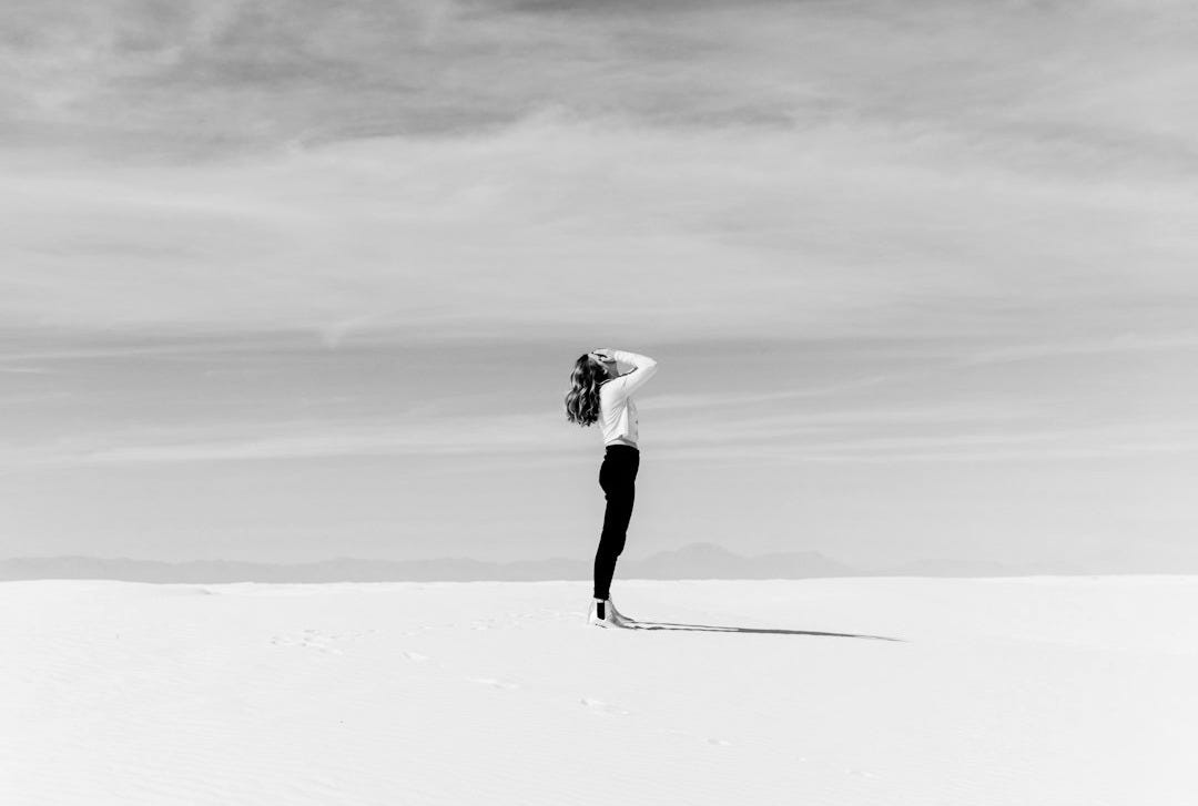 woman looking up to the sky while standing on white sand woman looking up to the sky while standing on white sand