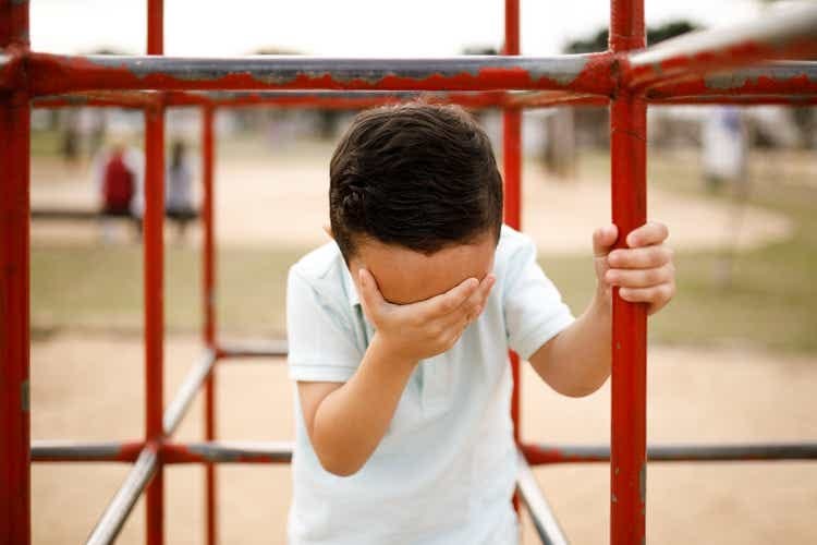 Boy doing a facepalm on a seesaw