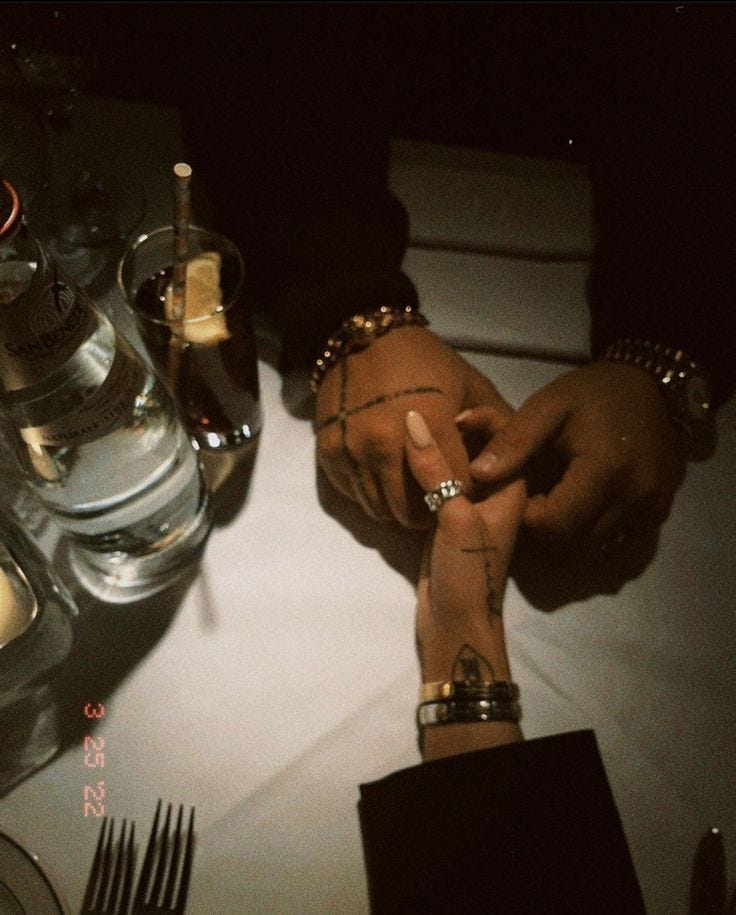 This may contain: two people sitting at a table with their hands on each other's wrists This may contain: two people sitting at a table with their hands on each other's wrists