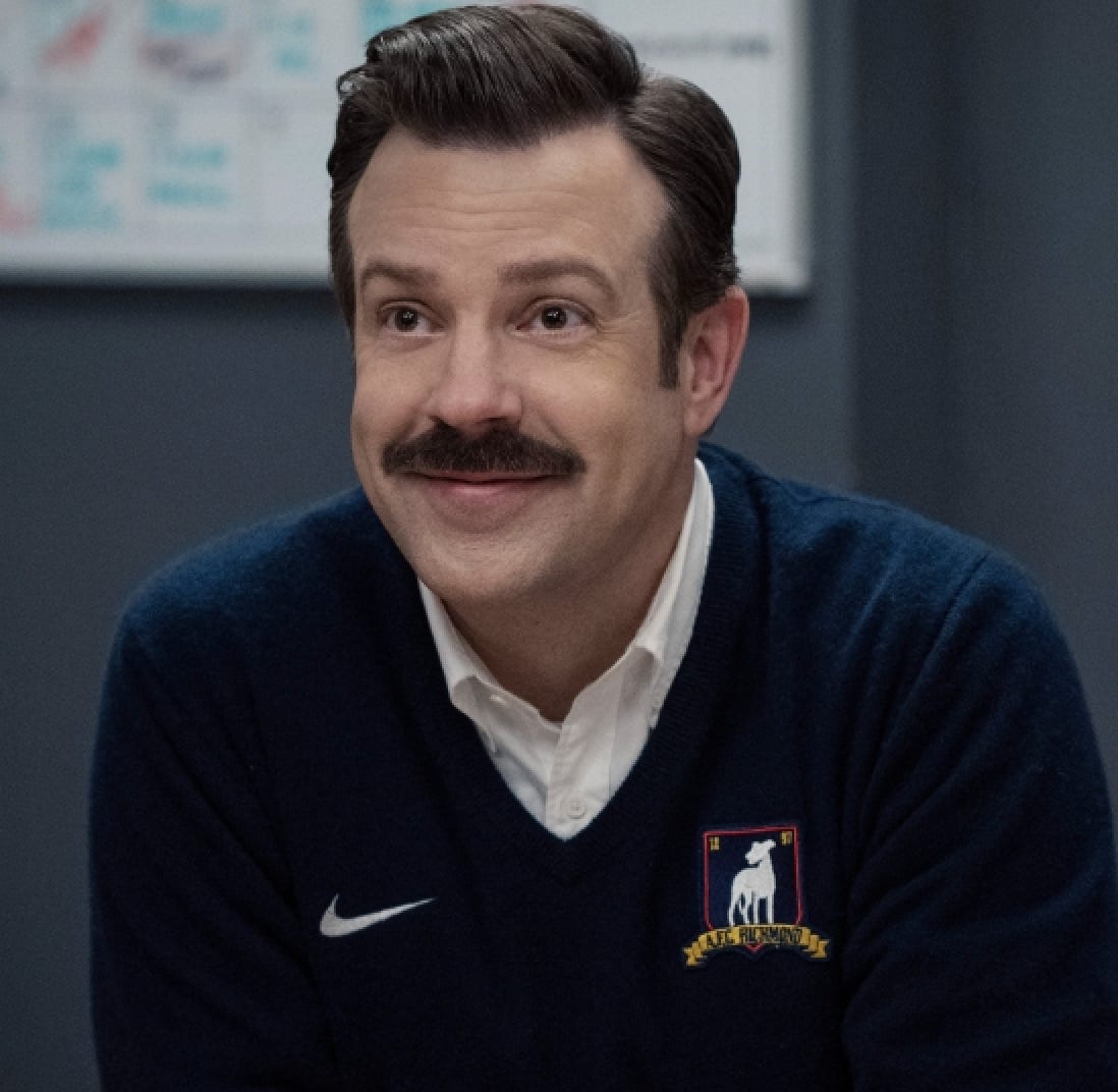 A still screen from the show Ted Lasso depicting the titular character.