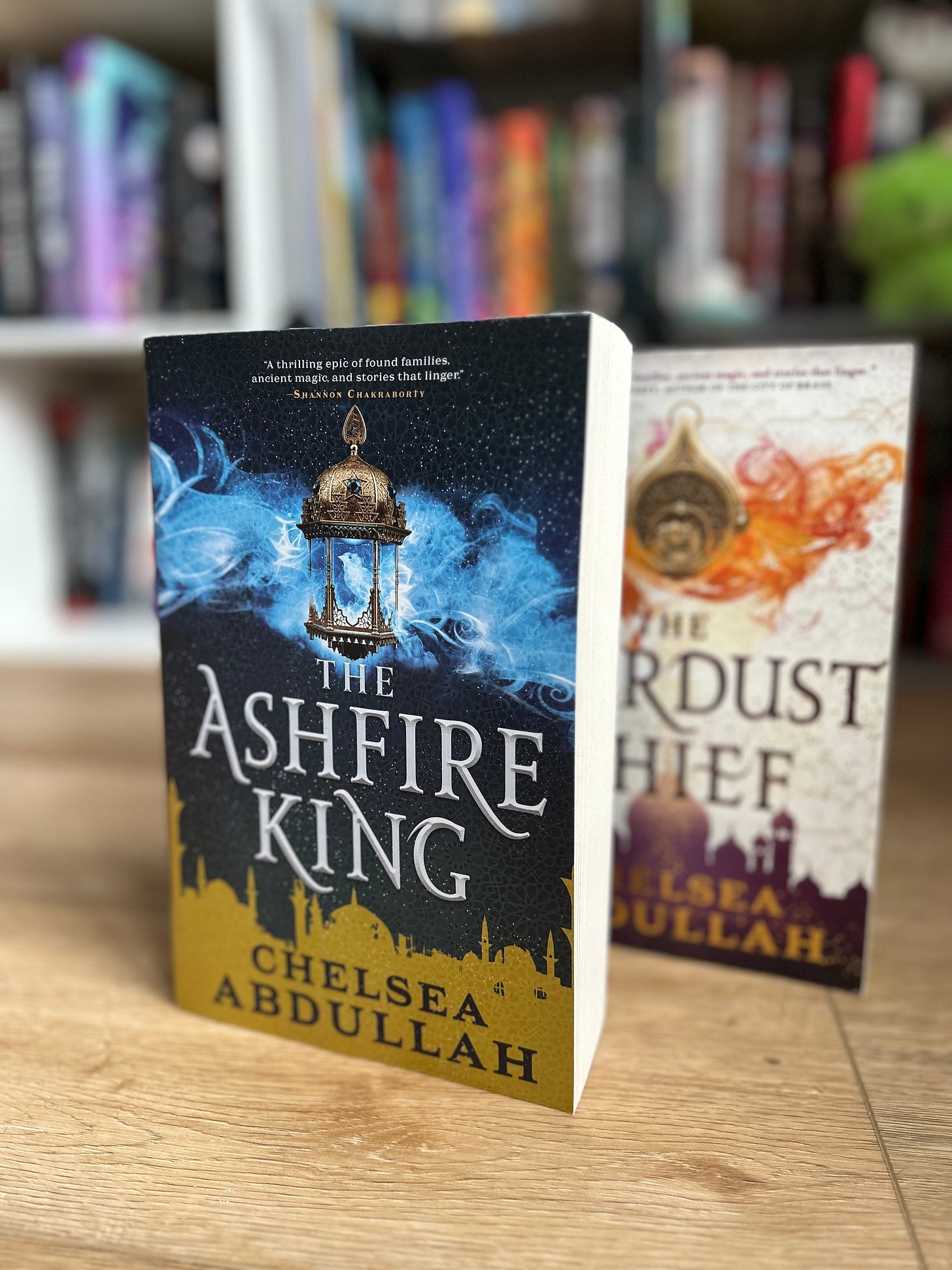 A paperback copy of THE ASHFIRE KING stacked in front of THE STARDUST THIEF paperback A paperback copy of THE ASHFIRE KING stacked in front of THE STARDUST THIEF paperback