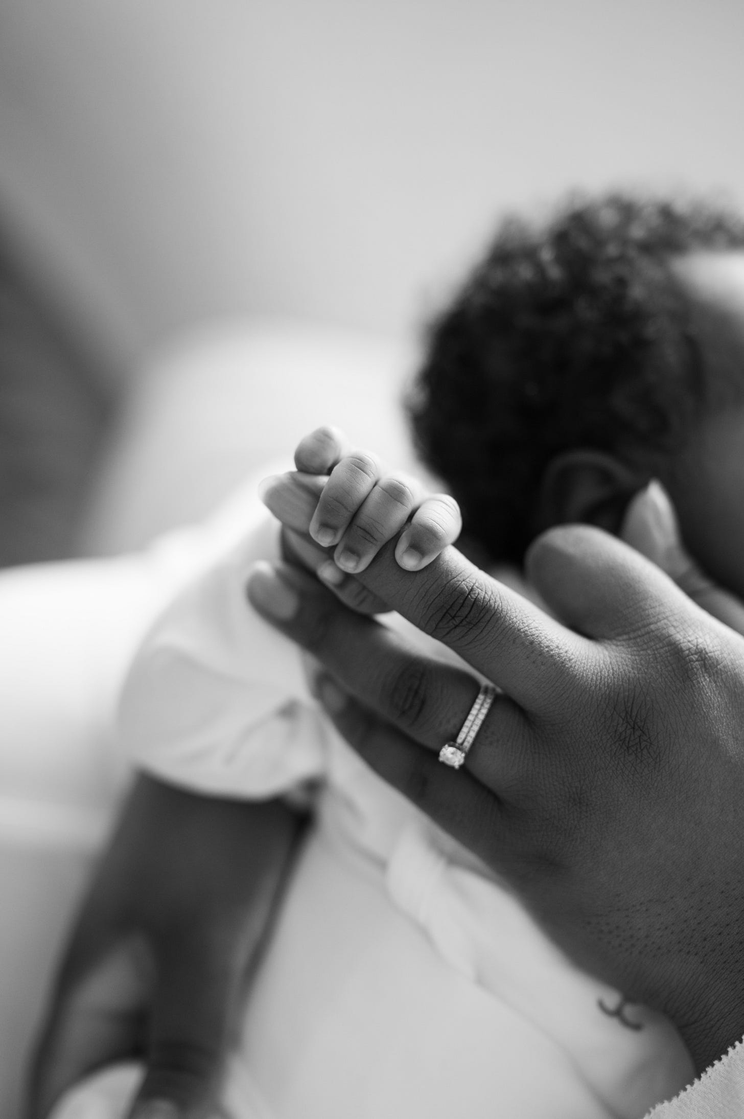 A tiny baby hand gripping a woman's middle finger
