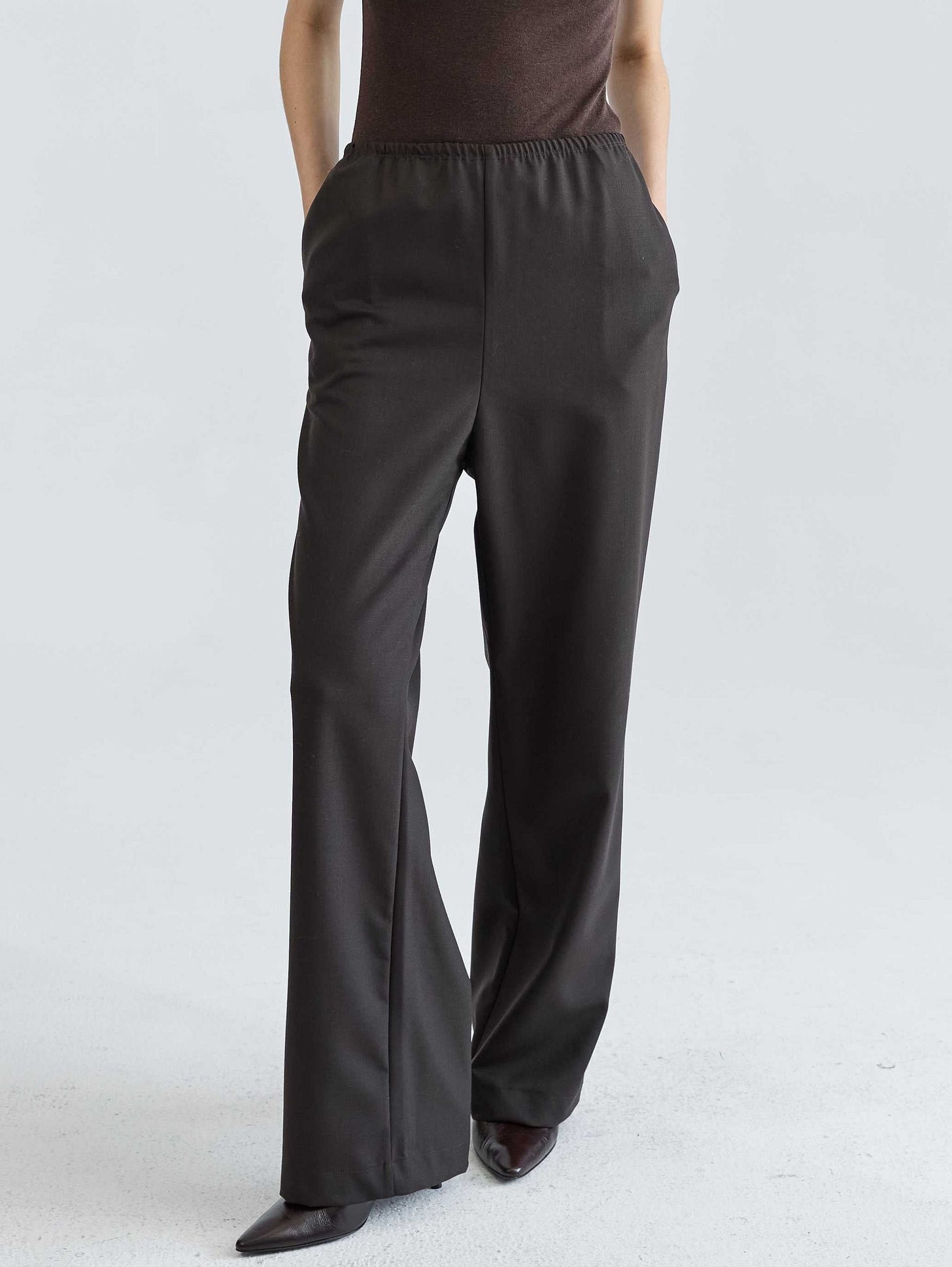 Woman wearing a brown top and dark brown pants on a white background Woman wearing a brown top and dark brown pants on a white background