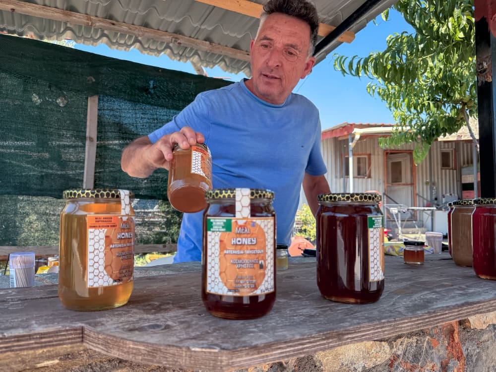 A man showing off some jars of honey that really were delicious.