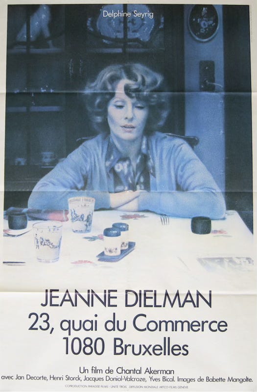 Promotional poster for Jeanne Dielman 23, quai du Commerce 1080 Bruxelles. Delphine Seyrig, a pale-skinned woman with brown hair and dressed in a blue cardigan and patterned blouse, sits at a table laden with tableware with her elbows resting on the table. She gazes down dreamily.