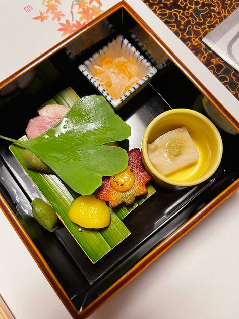 A collage of nine photos from Japan: a man in traditional kimono performing a tea ceremony; a tray of delicate kaiseki dishes with seasonal ingredients; a serene temple garden surrounded by moss and trees; a tatami room with sliding shoji doors; a mountain view with Mount Fuji in the distance; a bowl of Japanese dessert with green grapes and jelly; a Shinto wedding procession under a red umbrella; a moss-covered stone Buddha statue in a forest; and misty temple grounds framed by lush greenery.