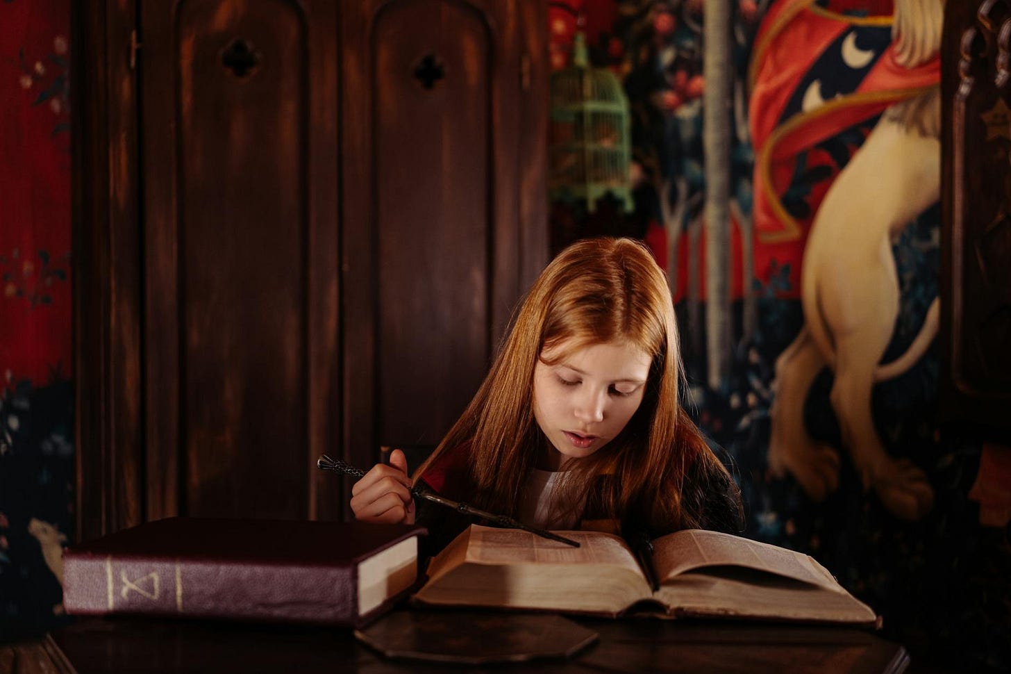 A girl dressed as a wizard reading a magic book.