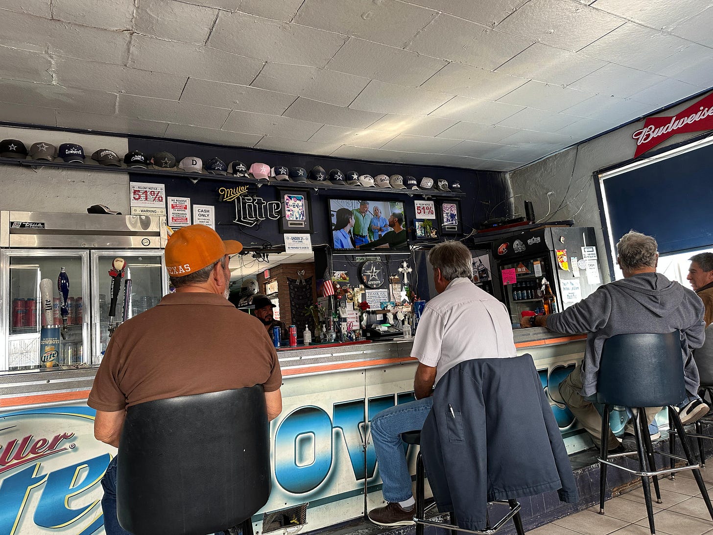 Four Mexican guys on stools along the Jockey bar, Dallas Cowboys memorabilia everywhere 