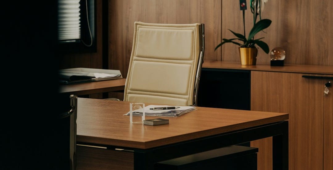 a desk with a chair and a vase of flowers
